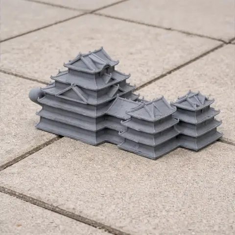 A gray 3D printed model of Azuchi Castle with tiered roofs, placed on paving stones.
