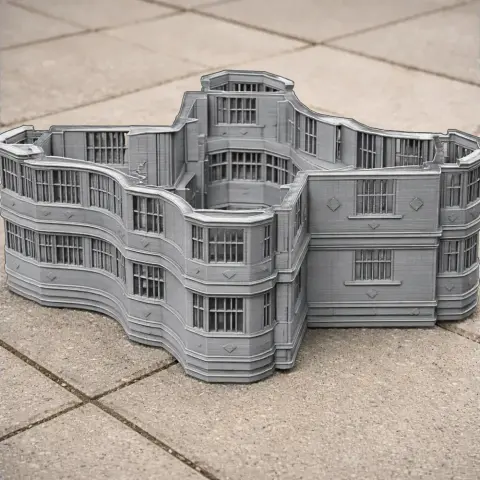 A detailed, wavy-edged model of a castle-like building with multiple windows and a central courtyard.