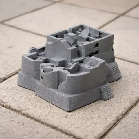 A gray 3D-printed model of a castle tower with detailed architectural features on a tiled surface.