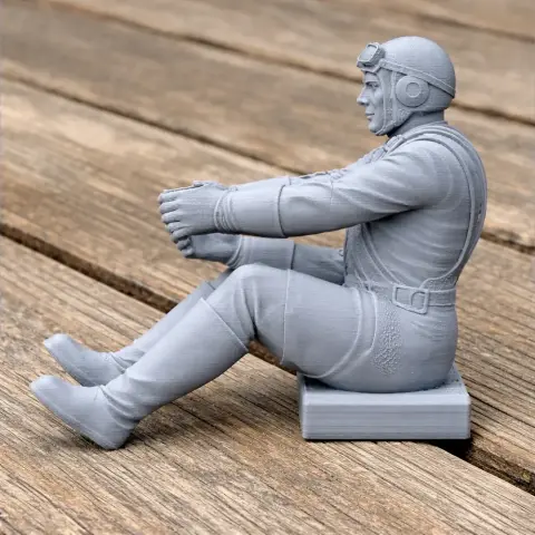 3D model of a seated WWII pilot in gear on a wooden surface, ready for 3D printing.