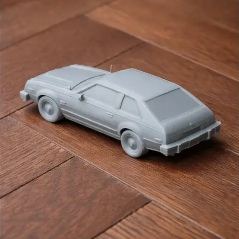 3D printed model of a classic AMC Spirit car, displayed on a wooden surface.