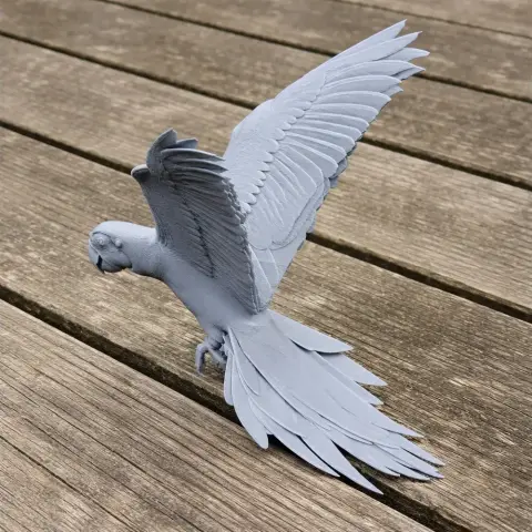 3D printed model of a parrot with wings spread, detailed feathers, perched on a wooden surface.