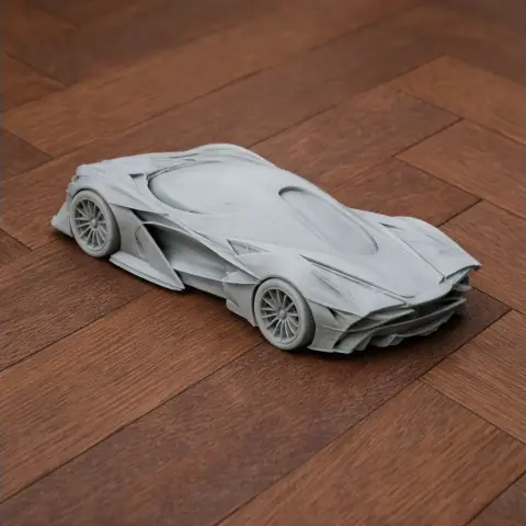3D printed model of a sleek, futuristic sports car on a wooden surface.