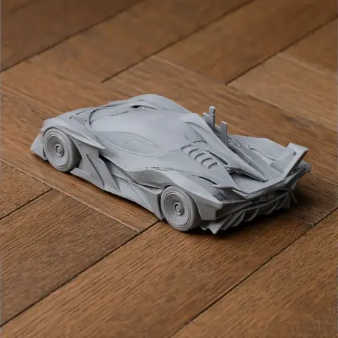 3D printed grey model of a sleek, aerodynamic sports car on a wooden surface.
