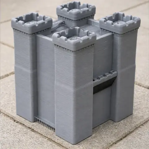 Gray 3D-printed model of a fortified castle with four corner towers on a tiled surface.