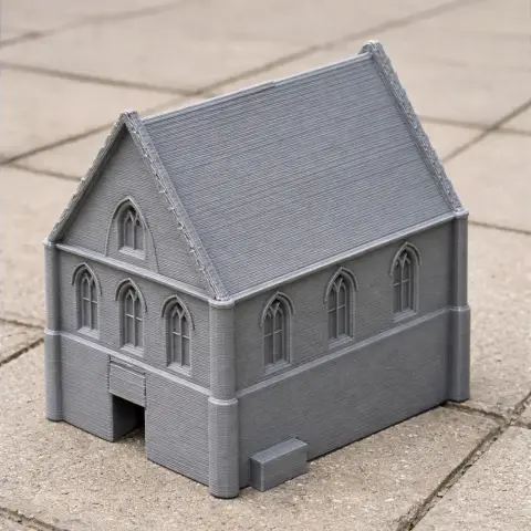 3D-printed model of a chapel with detailed windows and roof, set on a tiled surface.