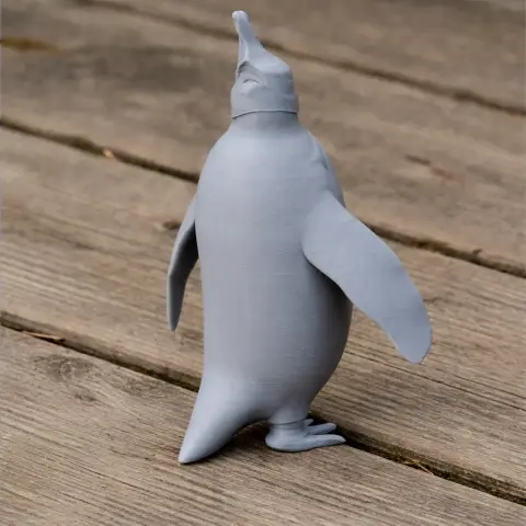 Gray 3D-printed model of a standing prehistoric penguin on a wooden surface.