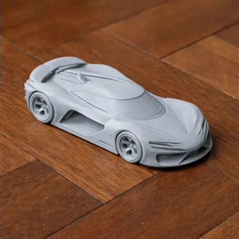 Futuristic 3D-printed car model with sleek, aerodynamic design on a wooden surface.