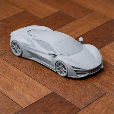 3D-printed model of a sleek sports car on a wooden surface, showcasing detailed curves and contours.