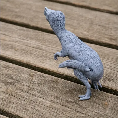 Gray 3D-printed Proceratosaurus model, standing on wooden planks.