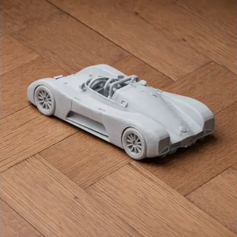 A 3D-printed model of a sleek racing car on a wooden surface.