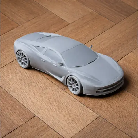 A detailed gray 3D printed model of a sleek sports car on a wooden surface.