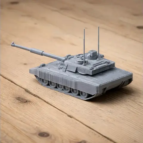 Gray 3D-printed tank model on a wooden surface, featuring a long barrel and antennas.