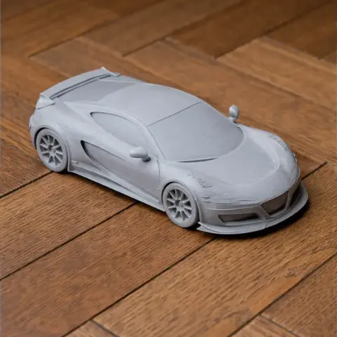 3D printed model of a sleek sports car on a wooden floor.