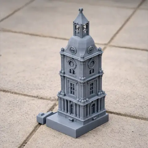 Gray 3D-printed clock tower model with detailed architecture on a tiled surface.