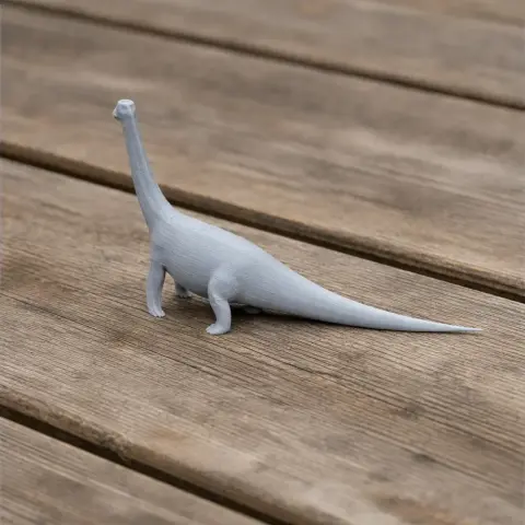 A small, gray 3D-printed model of a long-necked dinosaur on a wooden surface.