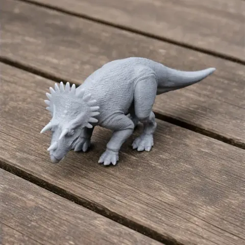 3D-printed model of a Regaliceratops dinosaur, featuring a frilled head and detailed limbs, on a wooden surface.