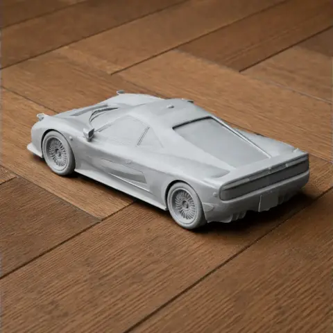 3D-printed scale model of a sleek sports car on a wooden surface.