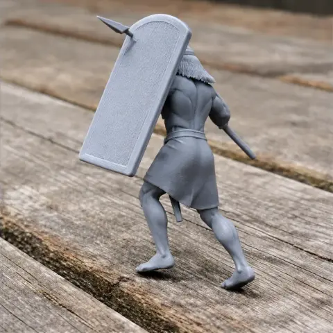 A 3D printed ancient warrior with a shield and spear, wearing a short tunic, on a wooden surface.