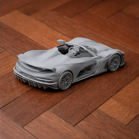 3D-printed scale model of a sleek, modern sports car on a wooden surface.