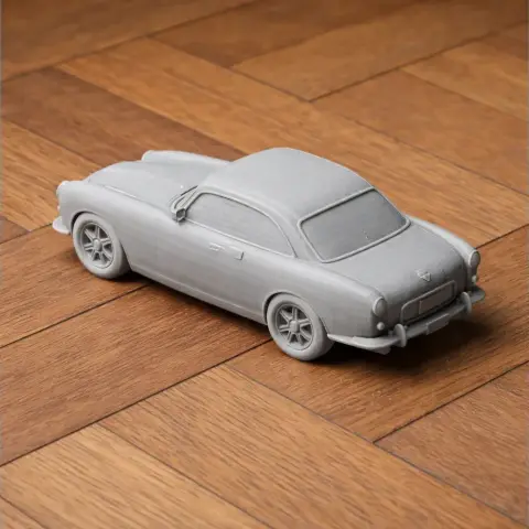 3D printed model of a classic Aston Martin car on a wooden surface.