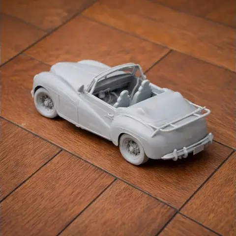 3D printed model of a vintage convertible car placed on a wooden surface.