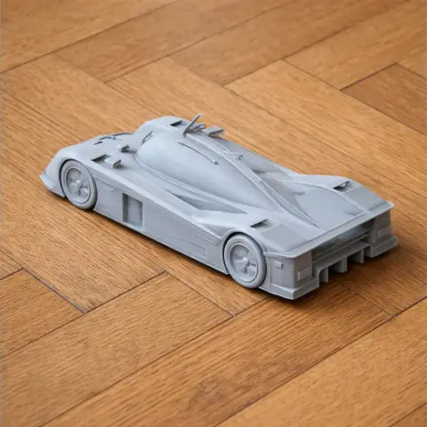 Gray 3D printed model of an Aston Martin AMR-One race car on a wooden floor.
