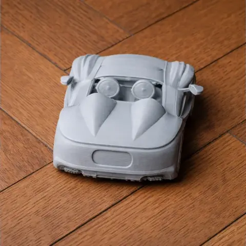 3D printed model of a streamlined sports car on a wooden surface.