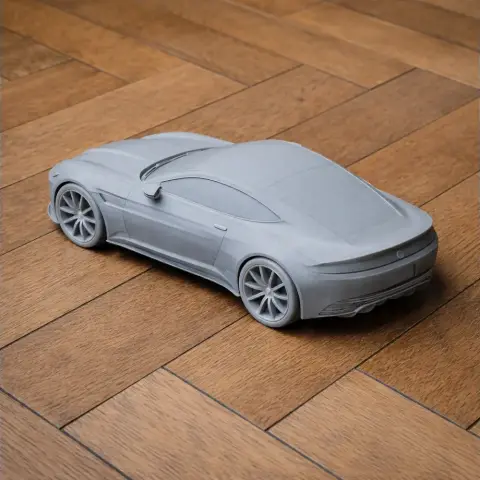 Gray 3D-printed Aston Martin DB10 scale model on wooden floor.