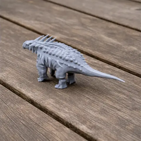 Gray 3D-printed Sauropelta model with spikes on its back, standing on a wooden surface.