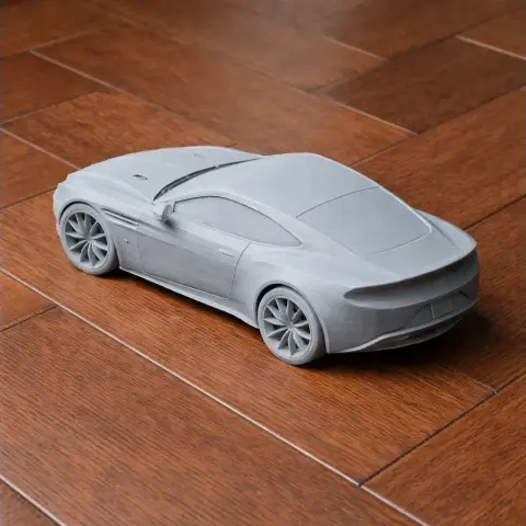 3D printed model of a sleek sports car, resembling an Aston Martin DB11, on a wooden surface.