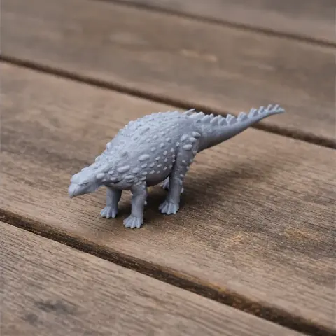 Gray 3D-printed model of an armored Silvisaurus dinosaur on a wooden surface.