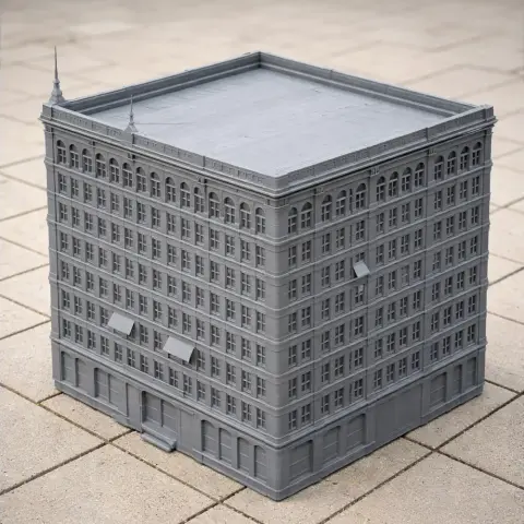 Gray 3D-printed model of an early skyscraper with detailed windows and roof, on a tiled surface.
