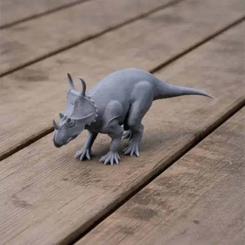 Gray 3D-printed model of a Spinops dinosaur with horns and frill, displayed on a wooden surface.