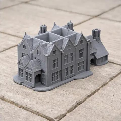 A detailed gray 3D-printed model of a historic manor with chimneys and gabled roofs.