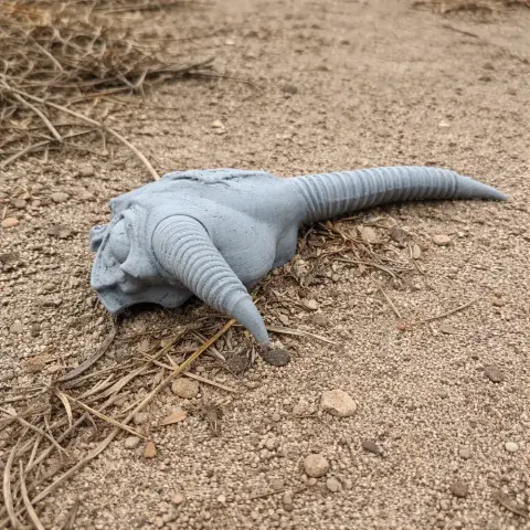 3D-printed gazelle skull replica with long curved horns, placed on sandy ground.