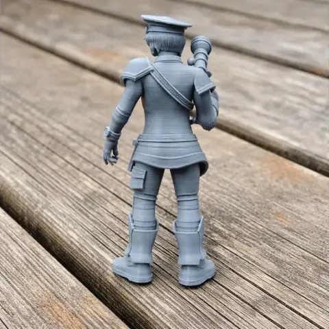3D printed soldier figure in uniform, holding a scoped rifle, stands on a wooden surface.