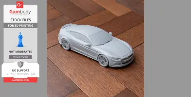 A 3D-printed model of a sleek Aston Martin Rapide car, placed on a wooden floor surface.