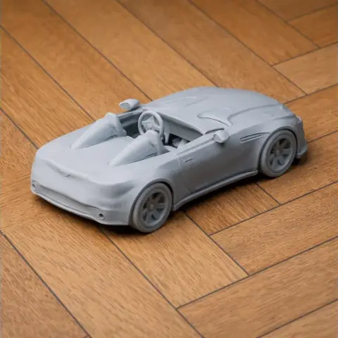 3D printed model of a convertible car on a wooden surface.