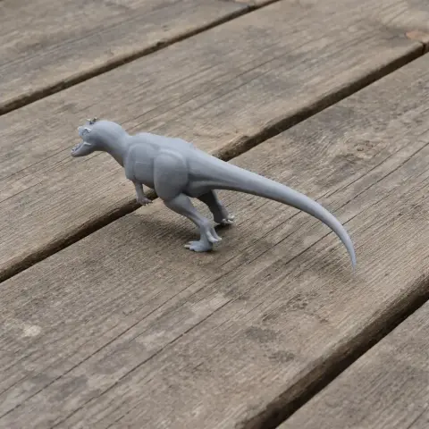 Gray 3D printed Stokesosaurus model on a wooden surface.