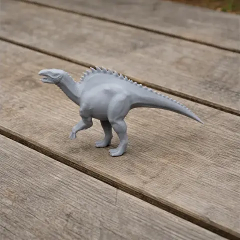 Gray 3D-printed dinosaur model with a spiked back, standing on wooden planks.