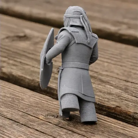 3D-printed ancient warrior figure holding a shield, viewed from the back on a wooden surface.