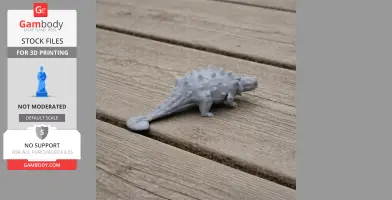 A small, spiky 3D-printed dinosaur model on a wooden surface.