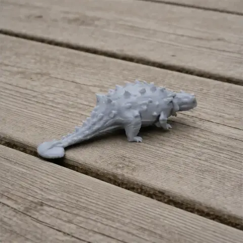 Gray 3D-printed model of Tianchisaurus on a wooden surface.