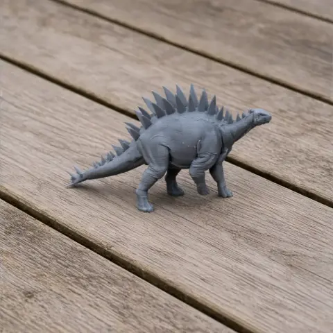 Gray 3D-printed model of a Tuojiangosaurus with spiky plates, on a wooden surface.