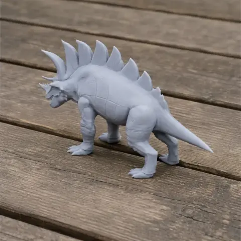 Gray 3D-printed model of a dinosaur with spiky back plates, standing on a wooden surface.