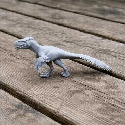 3D-printed Utahraptor model with detailed feathers and claws, standing on a wooden surface.