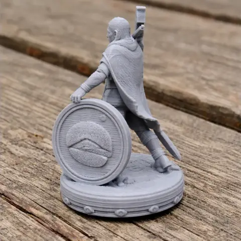 A 3D-printed Viking warrior figure with a shield and axe, standing on a textured base.