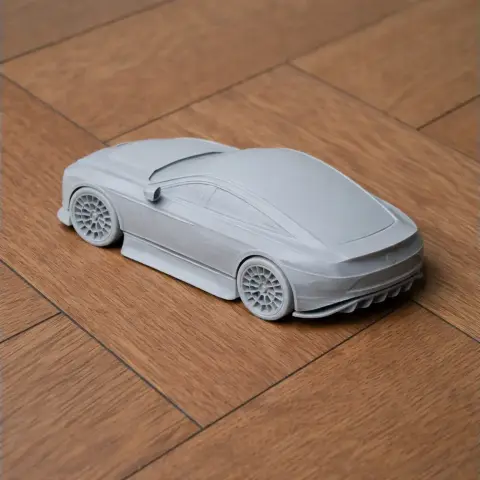 3D-printed scale model of a sleek sports car on a wooden surface.