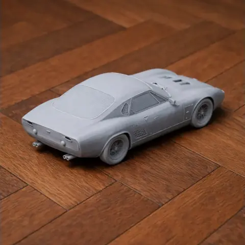 3D printed gray model of ATS 2500 GT car on wooden surface, rear side view.